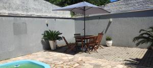 Casa com piscina duas quadras da praia في غواراتوبا: طاولة وكراسي مع مظلة على الفناء
