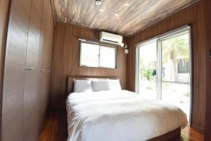 a bedroom with a large bed with a window at Seven Residence Music in Nago