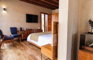 a bedroom with a bed and a tv and a chair at El Recinto Luxury Hotel in San Miguel de Allende