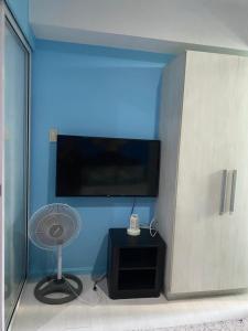 een kamer met een blauwe muur, een ventilator en een televisie bij Azure Urban Suite Room in Manilla