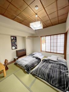 two twin beds in a room with a ceiling at AKANE Hostel あかね天然温泉旅館 in Mitsumata
