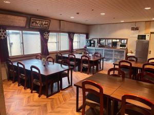 a restaurant with wooden tables and chairs and a kitchen at AKANE Hostel あかね天然温泉旅館 in Yuzawa