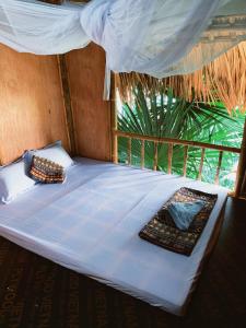a bed with a white sheet and a window at Lakeview Homestay Vu Linh in Yen Bai