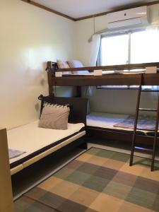 a dorm room with bunk beds and a window at Shimaotoya in Iriomote