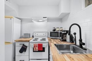 una cucina bianca con lavandino e piano cottura di 1BR+ Sofa Bed & Cozy Fireplace a Barrie