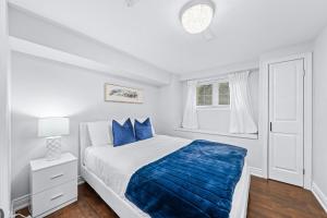 ein weißes Schlafzimmer mit einem großen Bett mit blauen Kissen in der Unterkunft 1BR+ Sofa Bed & Cozy Fireplace in Barrie