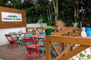 una terraza con mesas y sillas rojas y verdes en Cabanas do Lorde, en Praia do Rosa