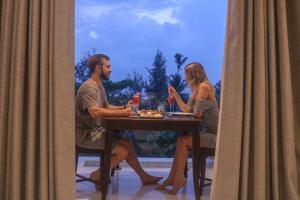 Ein Mann und eine Frau sitzen an einem Tisch in der Unterkunft Mzion Hotel Weligama in Weligama