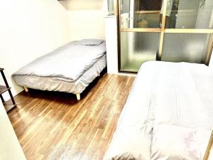 1 dormitorio con 2 camas y suelo de madera en Hana House West Shinjuku, en Tokio