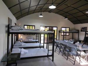 Zimmer mit mehreren Etagenbetten, Tischen und Stühlen in der Unterkunft Camp Palo Bandera in Calatagan
