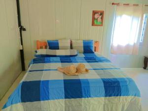 Una cama azul y blanca con dos sombreros. en Lung peiyk homestay, en Ban Bang Bao