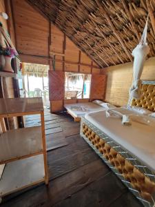 a room with three beds and a wooden ceiling at Palos Locos Baru in Cartagena de Indias