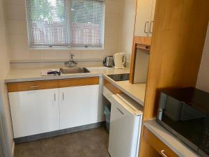 a small kitchen with a sink and a microwave at Aaron Court Motel Whangarei in Whangarei