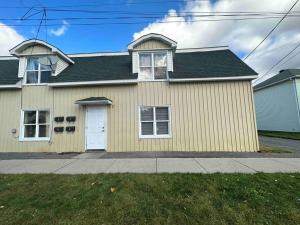 a yellow house with a white door at Freshly Renovated 2 bedroom unit in Cornwall