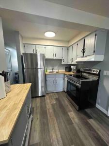 a kitchen with white cabinets and a stainless steel refrigerator at Freshly Renovated 2 bedroom unit in Cornwall
