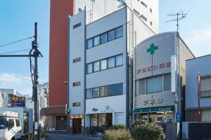 a tall white building with a green cross on it at SLEEPLAB 高輪 -睡眠特化型Hotel- in Tokyo
