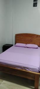 a bed with a wooden frame and purple mattress at Mini Departamento Iquitos 1243 in Iquitos