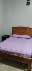 Cama con marco de madera y colchón morado en Mini Departamento Iquitos 1243 en Iquitos