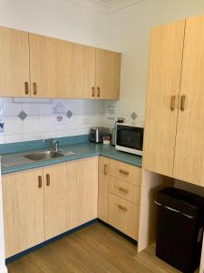 湯斯維爾的住宿－Accommodation @ 134 Denham，厨房配有木制橱柜、水槽和微波炉