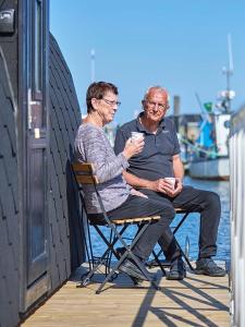 two men sitting in chairs on a dock at Boathouses - Overnat på vandet ved Limfjorden in Vinderup