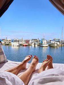 a person laying on a bed with their feet up on the bed at Boathouses - Overnat på vandet ved Limfjorden in Vinderup