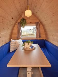un tavolo in legno in una camera con divano blu di Boathouses - Overnat på vandet ved Limfjorden a Vinderup