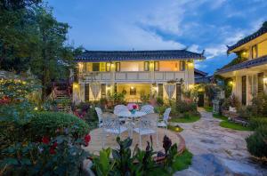 a patio with a table and chairs in front of a house at Rose Garden Lijiang in Lijiang