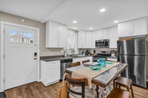 a kitchen with white cabinets and a table with chairs at Seaside Cottage: A 'MyShoreCottage' Property in Seaside Heights