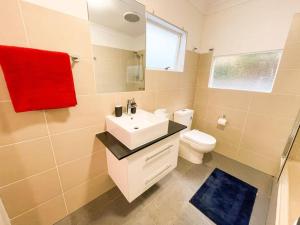 een badkamer met een wastafel, een toilet en een rode handdoek bij A Beautiful Terrace House with Parking & Courtyard in Melbourne