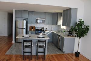 una cucina con armadi grigi e un'isola con sgabelli da bar di Cozy & Deluxe Apartment - EZ Access to NYC a Newark