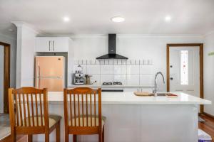 a kitchen with a counter and two chairs and a sink at Swan Lake Escape in Sussex inlet
