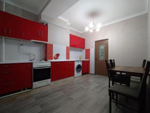 比什凱克的住宿－AURA on Isanov street 118，一间带红色橱柜和桌子的厨房以及一间用餐室