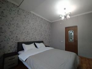 ビシュケクにあるAURA on Isanov street 118のベッドルーム1室(白いシーツと花の壁紙を使用したベッド1台付)
