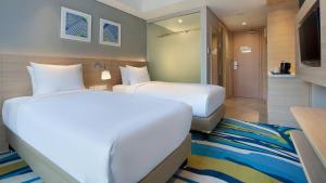 a hotel room with two beds and a television at Holiday Inn Express Jakarta Wahid Hasyim, an IHG Hotel in Jakarta