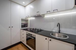 a white kitchen with a sink and a stove at Story Bridge & River View 2B1B Apt w Free Parking! in Brisbane
