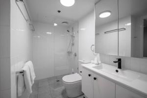 a white bathroom with a toilet and a sink at Story Bridge & River View 2B1B Apt w Free Parking! in Brisbane