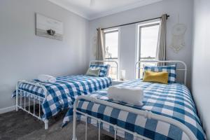 two beds in a room with blue and white checks at The Inlet at Sussex in Sussex inlet