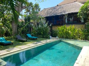 a swimming pool in front of a villa at Little Tree House in Sanur
