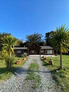 Una casa con dos palmeras y un camino de grava. en Lodge Dream Pucon, en Pucón