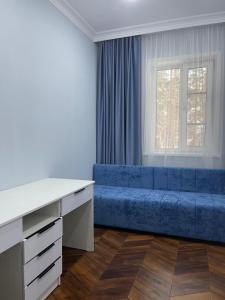 een woonkamer met een blauwe bank voor een raam bij SULTAN PLAZA Borovoe in Borovoye