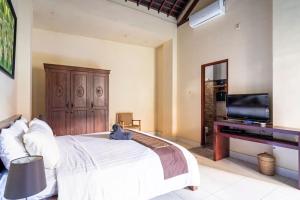 a bedroom with a bed and a flat screen tv at Villa Kenanga in Meninting By The Beach in Mataram