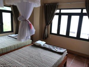 2 Betten in einem Zimmer mit Fenstern und einer Braut in der Unterkunft Homestay Huyền Thoại Cao Nguyên Đá 