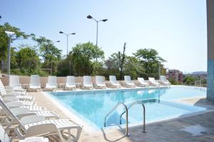 a pool with white chairs and a bunch ofitures at Hotel Ray in Sozopol