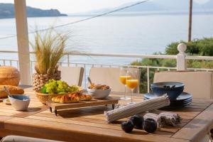 - une table en bois avec de la nourriture et des boissons sur un balcon dans l'établissement Ionian Calm Villas, à Vasiliki
