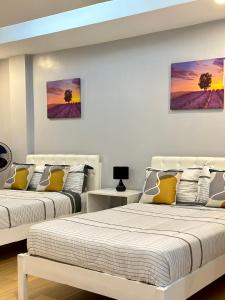 2 Betten in einem weißen Zimmer mit Gemälden an der Wand in der Unterkunft D' Beach Resort in Puerto Princesa