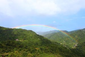 a rainbow in the sky over a green mountain at 森活藝術文旅 in Shiding