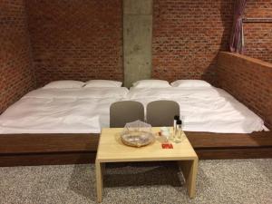 a bed with white sheets and a table with glasses on it at 森活藝術文旅 in Shiding