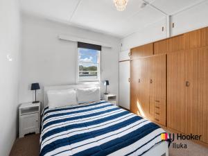 une chambre avec un lit avec une couverture rayée bleue et blanche dans l'établissement Fisherman's Cottage, à Iluka