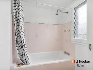 La salle de bains est pourvue d'une baignoire avec rideau de douche. dans l'établissement Fisherman's Cottage, à Iluka 5 autres photos