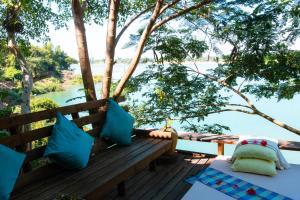 un banc sur une terrasse avec vue sur l'eau dans l'établissement Mekong Bird Resort & Hotel, à Stœ̆ng Trêng